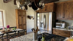 Une cuisine avec des meubles en bois, un réfrigérateur en acier inoxydable, un four à micro-ondes et une cuisinière à gaz. On y trouve des chaises et une table décorée de fleurs.
