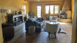 Un salon chaleureux avec une cheminée, un canapé en cuir et un fauteuil blanc.