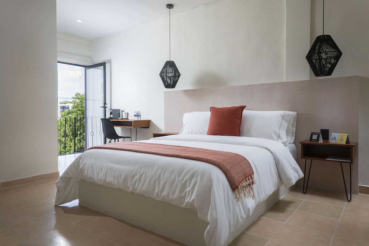 Ein modernes Schlafzimmer mit einem großen Bett, einem Schreibtisch und Blick ins Grüne.