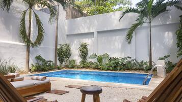 A pool area with lounge chairs and a small pool.