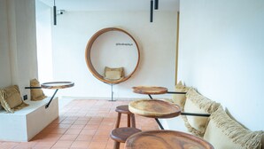 Un intérieur moderne avec des tables rondes en bois, un canapé blanc et un fauteuil suspendu.
