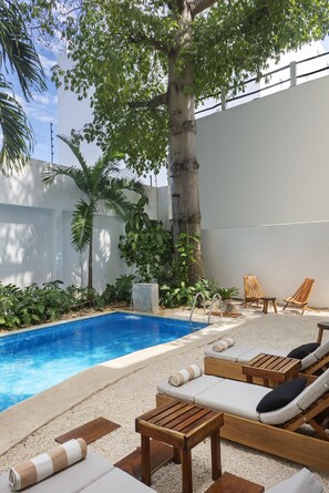 Una piscina al aire libre, sillones reclinables de piscina