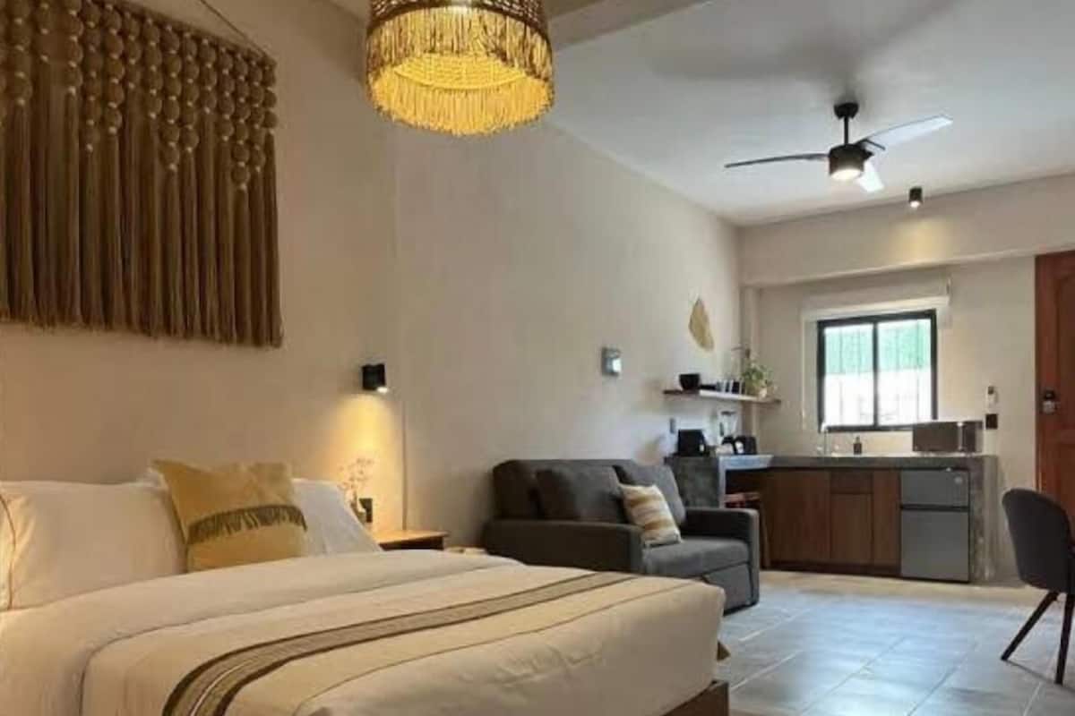 Ein Schlafzimmer mit Bett, einer Couch, einer Essecke und einer Küche.