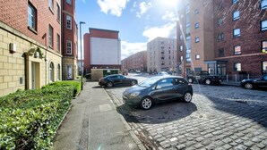A street view with a row of brick buildings, a paved sidewalk, and parked cars. - GuestReady - Spacious 2BR in Leith (Leith)