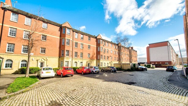 A multi-story brick building with a parking area in front. - GuestReady - Spacious 2BR in Leith (Leith)