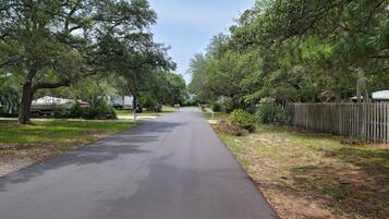 Une rue résidentielle bordée d’arbres et délimitée par une clôture en bois.