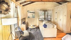 Una habitación acogedora de estilo cabaña con techo de madera, un sofá blanco, una pequeña mesa redonda y una lámpara.