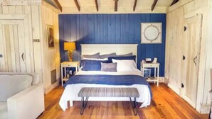 Un dormitorio con una cama grande, pisos de madera y una pared azul de acento.
