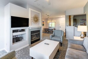 A modern living room with a flat-screen TV, fireplace, and comfortable seating.