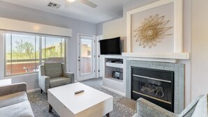 A modern living room with a fireplace, a television, and a large window with a view of the outdoors.