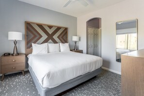 Une chambre d’hôtel avec un grand lit, deux tables de chevet avec des lampes, une armoire et un miroir.