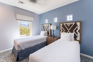 A hotel room with two beds, a window, and a view of the outdoors.