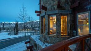 A stone building with large windows, a wooden deck, and a view of snow-covered mountains. - Lorian #2 | Walk-Everywhere (Telluride)