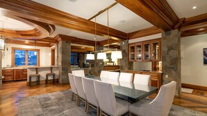 A spacious dining area with a large table and chairs, wooden beams on the ceiling, and stone accents. - Lorian #2 | Walk-Everywhere (Telluride)