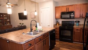 A kitchen with wooden cabinets, a black stove, a microwave, and a dishwasher. - Peaceful 2-bedroom Townhome Just Steps Away from the Excitement of Pigeon Forge. (Pigeon Forge)