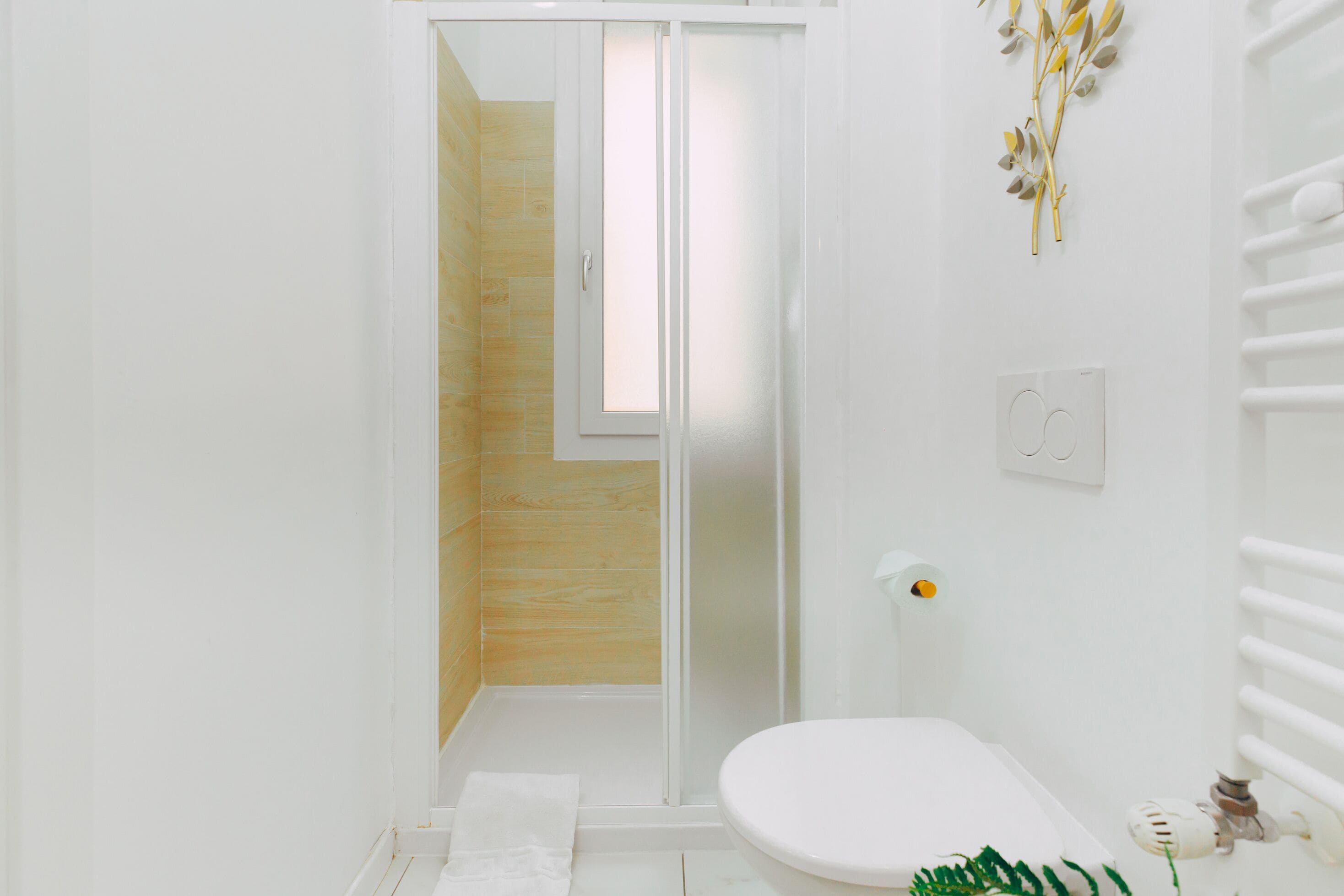 Une salle de bain avec des toilettes blanches, une douche en verre et un mur en bois.