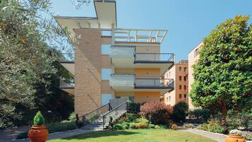A multi-story building with balconies, a staircase, and a well-maintained garden with potted plants.