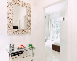 Un bagno moderno con un mobile lavabo bianco, uno specchio grande e decorativo e un armadietto in vetro con oggetti decorativi.