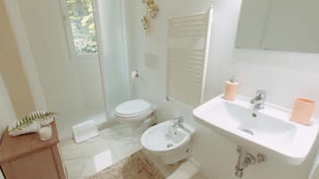 Un baño con inodoro, bidé, lavabo y espejo.