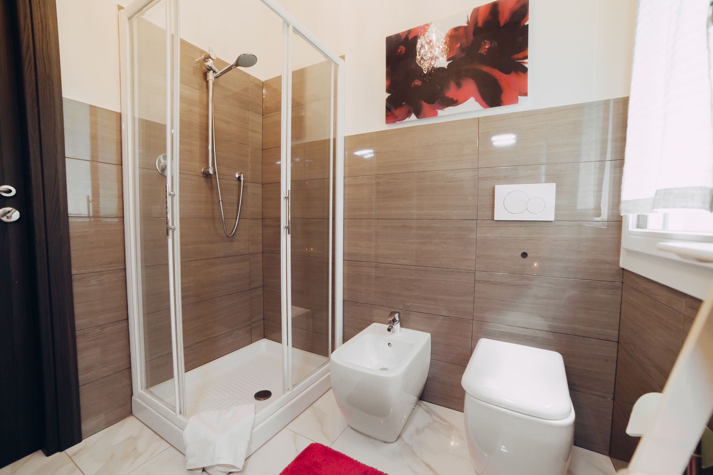 A modern bathroom with a glass-enclosed shower, a bidet, and a toilet.