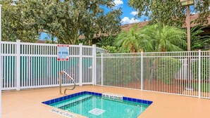 A pool area with a white fence, a diving board, and a sign indicating no diving.