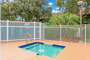 A swimming pool with a white fence, a diving board, and a sign indicating no diving.