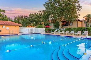 A swimming pool with clear lane dividers, a lifeguard stand, and lounge chairs.