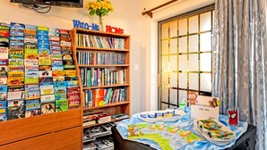 A room with a bookshelf filled with books, a welcome sign, a table with snacks, and a Spider-Man themed candle.
