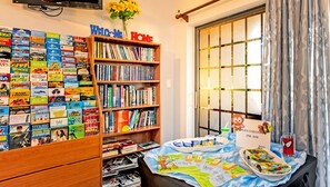 A room with a bookshelf filled with books, a welcome sign, a table with snacks, and a Spider-Man themed candle.