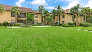 A residential building with a flat roof, multiple balconies, and a well-maintained lawn.