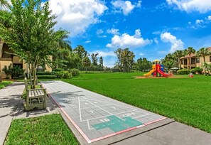 Ein Park mit einem Spielplatz, einem barrierefreien Weg und umgebender Bepflanzung.