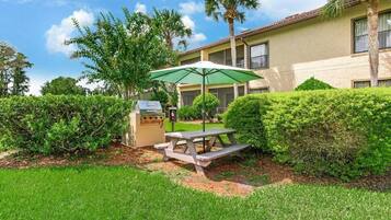 Enjoy meals and gatherings in a serene outdoor space surrounded by lush greenery and a classic building.