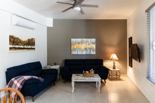 A living room with a ceiling fan, two sofas, a coffee table, and artwork on the walls.