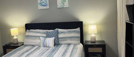 A bedroom with a bed, two bedside tables, a ceiling fan, and wall art.