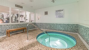 A spa area with a hot tub, a wooden bench, and a tiled floor.