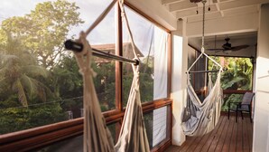 A wooden deck with two hammocks and a table, overlooking a lush garden. - Gorgeous Entire Floor Condo - 3 BR Private Balcony & Rooftop Pool (West Bay)
