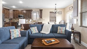 A modern living room with a blue sofa set, a wooden coffee table, and a kitchen in the background. - Sandy, UT home. Near the best skiing in the world (Sandy)