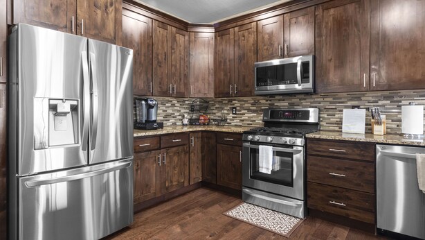 A modern kitchen with wooden cabinets, stainless steel appliances, a microwave, and a gas stove. - Sandy, UT home. Near the best skiing in the world (Sandy)