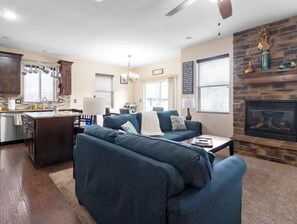 Cozy living space with a central seating area, kitchenette, and stone fireplace.