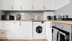 Eine moderne Küche mit weißen Schränken, einer Waschmaschine, einer Mikrowelle und einem Backofen.