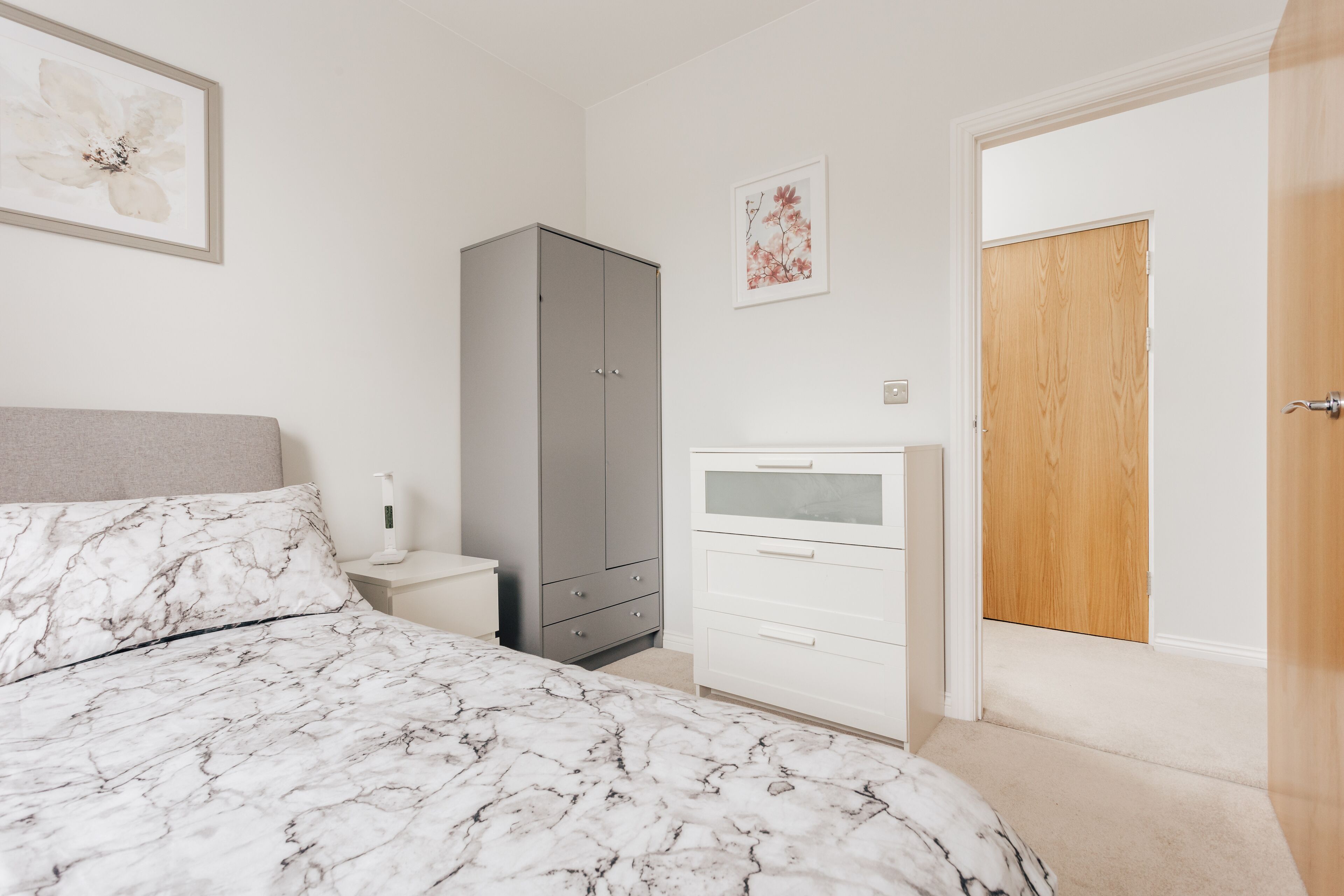 A bedroom with a bed, a wardrobe, a nightstand, and a door.