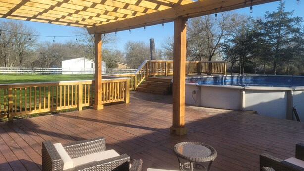 A wooden deck with outdoor furniture, a pool, and a pergola structure. - The Perfect Getaway (Elgin)