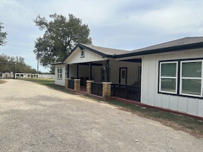 A two-story building with a covered porch and a fenced area. - The Perfect Getaway (Elgin)