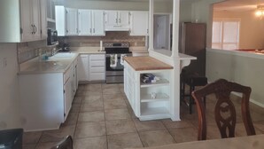 A compact kitchen with white cabinets, a wooden countertop, and a built-in oven. - The Perfect Getaway (Elgin)