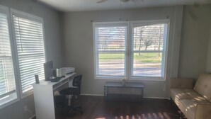 A room with a desk, office chair, and a sofa. There are two windows with blinds, and a ceiling fan is visible. - The Perfect Getaway (Elgin)