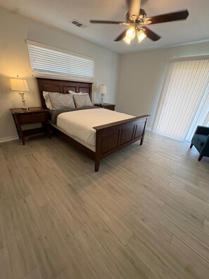 A bedroom with a bed, nightstands, a ceiling fan, and a window with blinds.