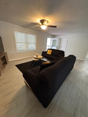 A living room with a black sofa, a coffee table, and a ceiling fan.