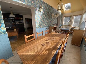 Un comedor con una mesa y sillas de madera, una estantería y un papel tapiz estampado.