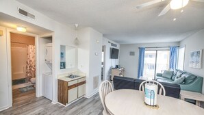 Un espacio habitable compacto con kitchenette, comedor y zona de estar con vistas al exterior.
