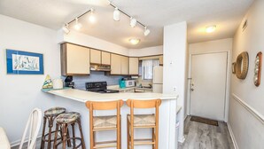 Una cocina compacta con una isla central, taburetes de bar y una mesa de comedor.